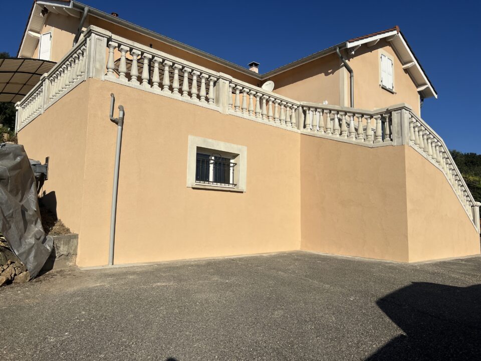 Maison avec balcon et fenêtre grillagée.