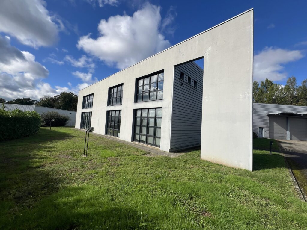 Bâtiment cubique avec façade claire et fenêtres noires par 3R Façades