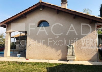 Maison beige avec grande fenêtre et fontaine.