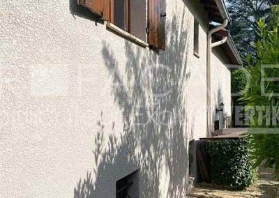 Façade de maison avec fenêtre et plante grimpante.