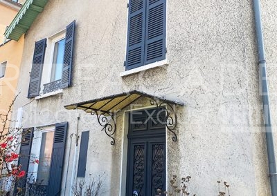 Façade de maison avec volets et auvent.