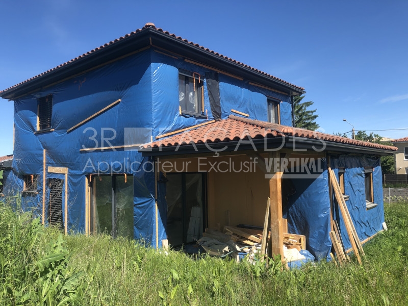 Maison en construction sous bâche bleue.