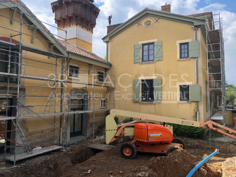 Construction de bâtiment avec échafaudages et nacelle élévatrice.