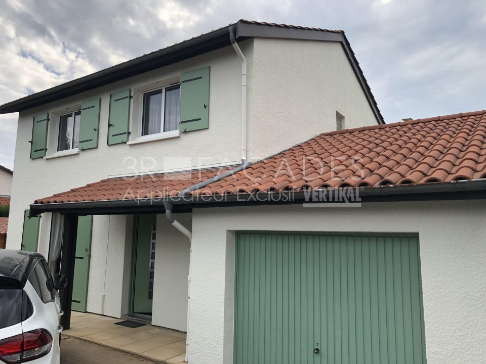 Maison blanche avec volets verts et porte de garage.