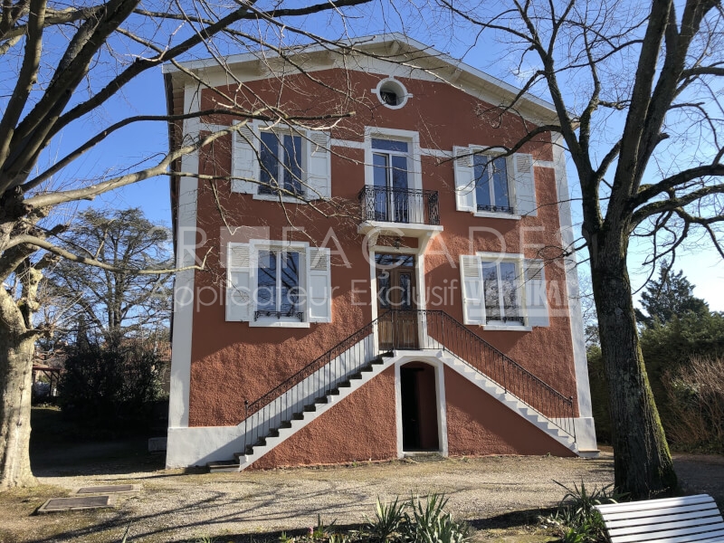 Maison rouge avec escaliers et fenêtres blanches.