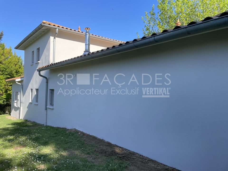 Maison blanche avec gouttières et cheminée.