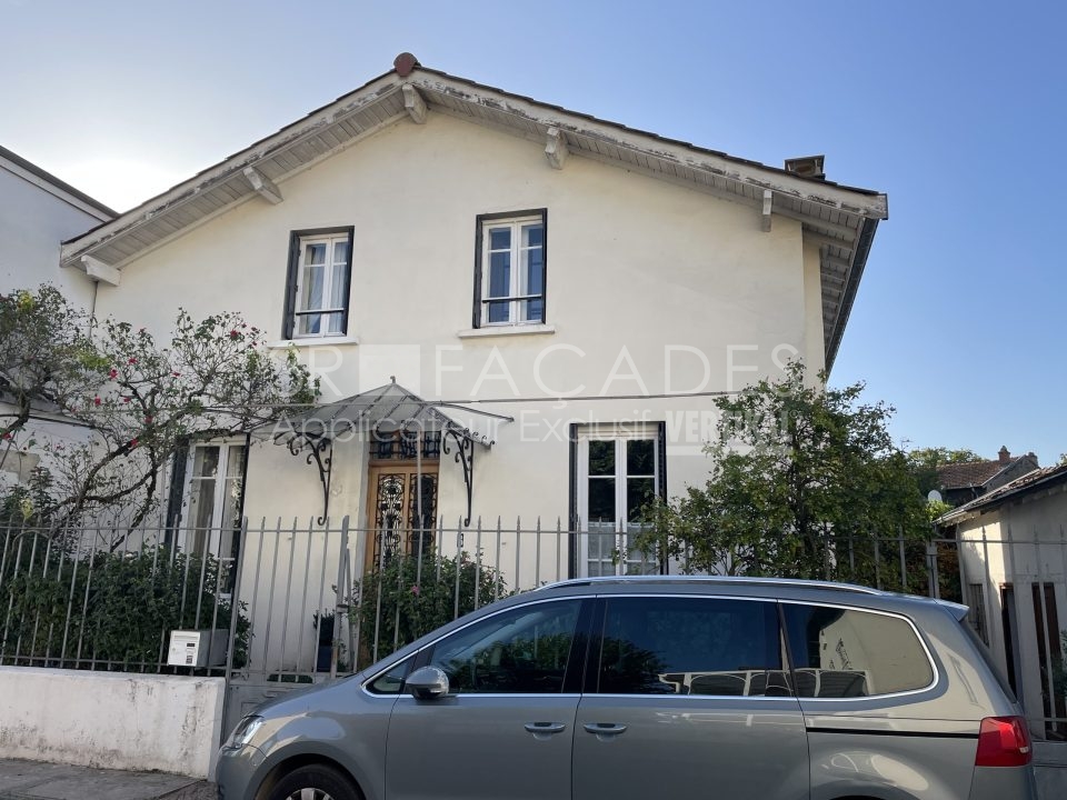 Maison blanche avec voiture grise devant.