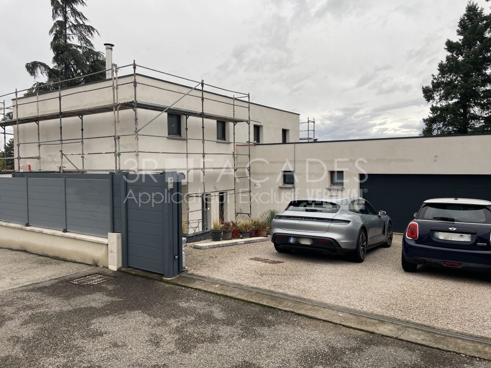 Maison en construction avec 3R Façades, voitures garées devant.