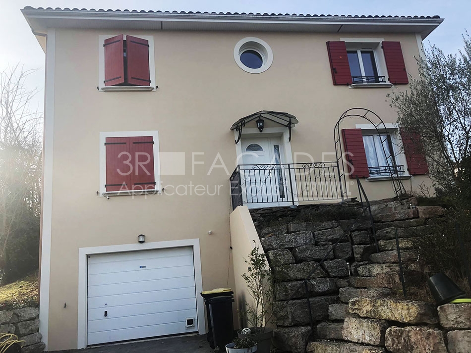 Maison avec volets rouges et porte de garage blanche.