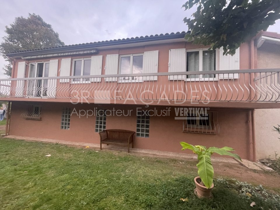 Maison à deux étages avec balcon et fenêtres grillagées.