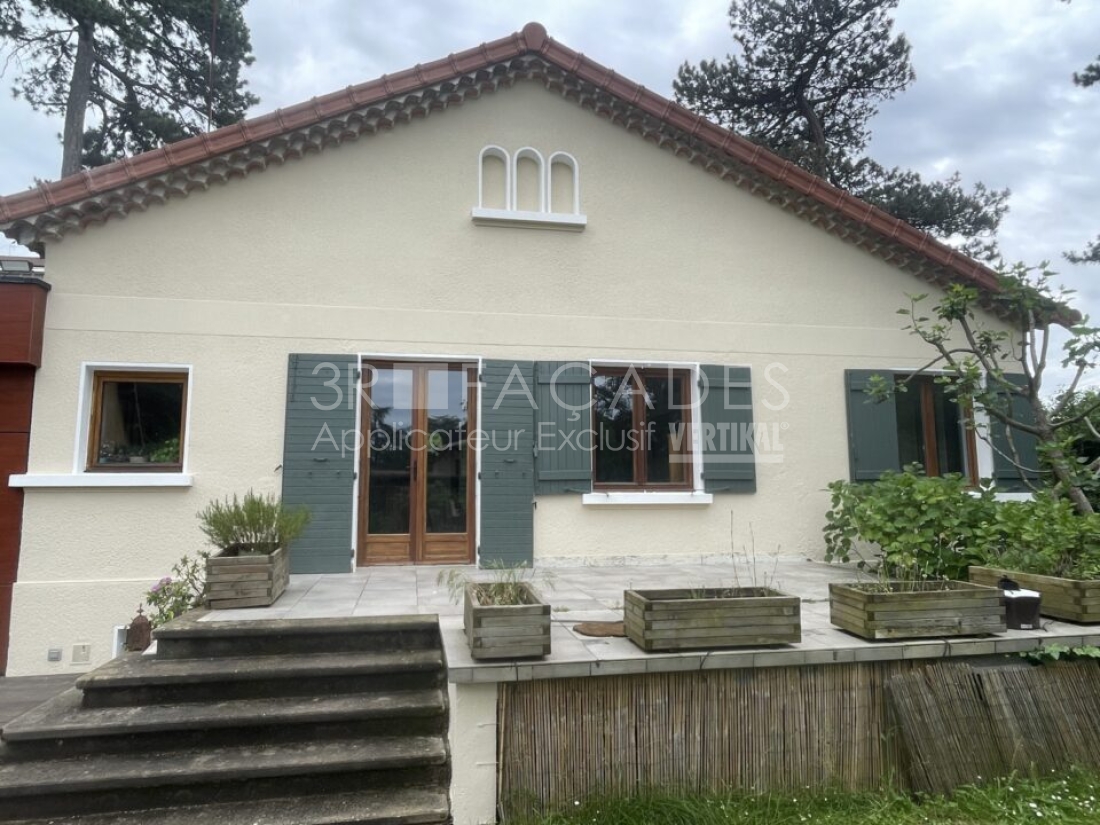 Maison blanche avec volets verts et fenêtres en bois.