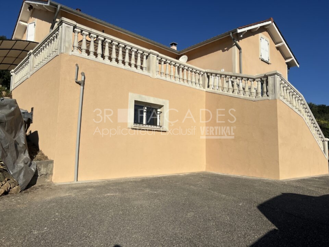 Maison avec balcon en pierre, façade beige, fenêtre avec barreaux