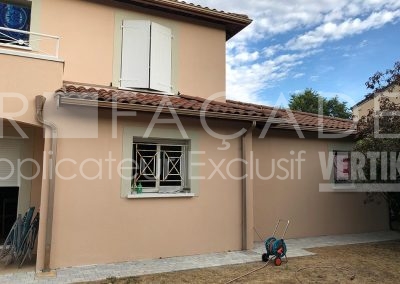 Maison peinte en beige avec fenêtre grillagée.